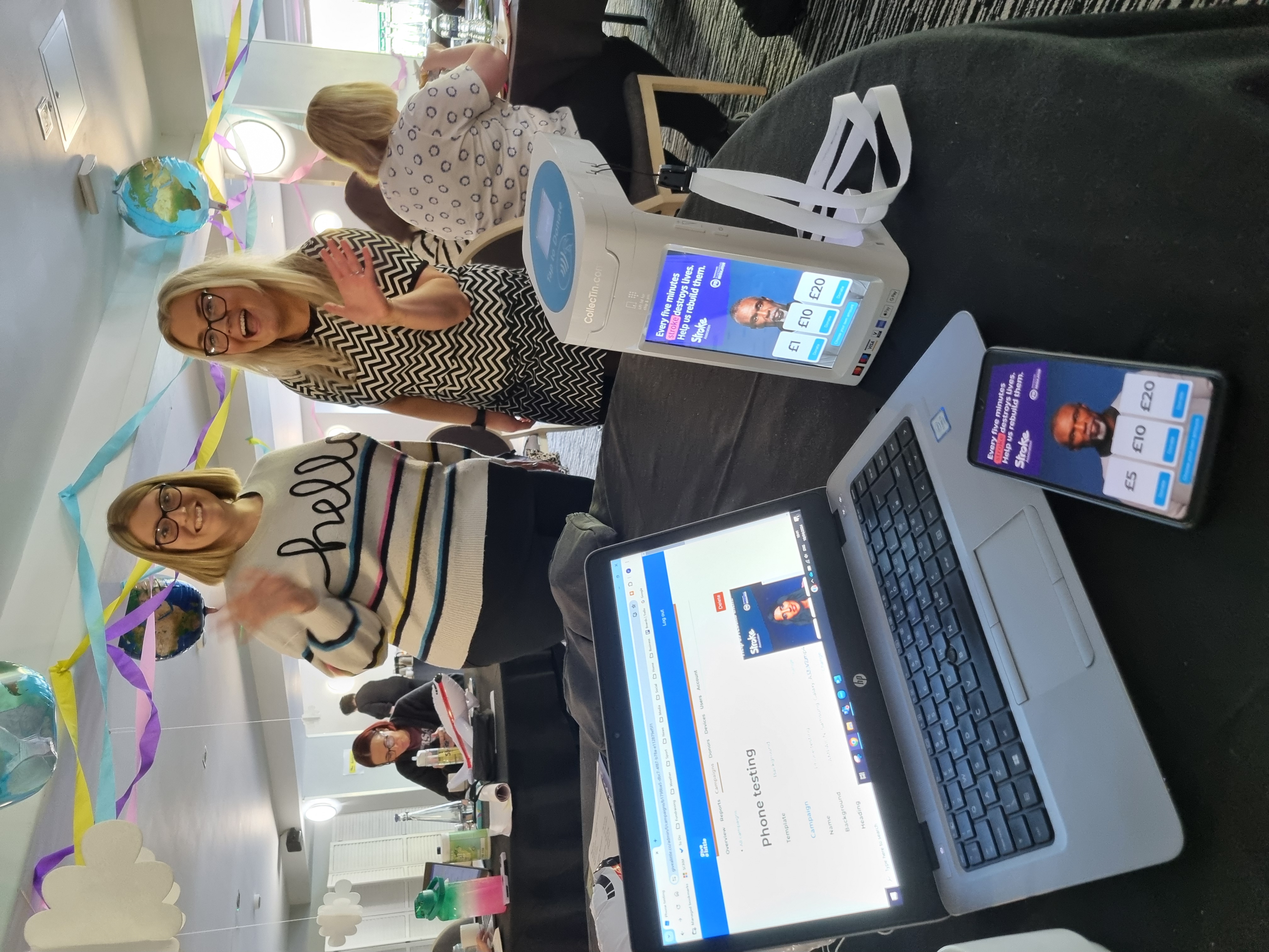 image of a laptop, mobile phone and CollecTin device on table, with the donation tech displayed