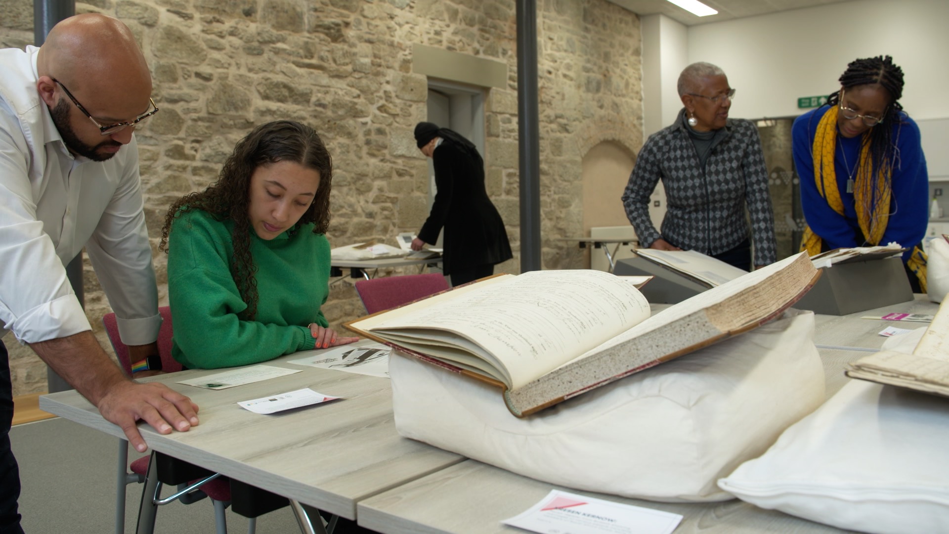 5 people reading manuscripts in one of their workshops