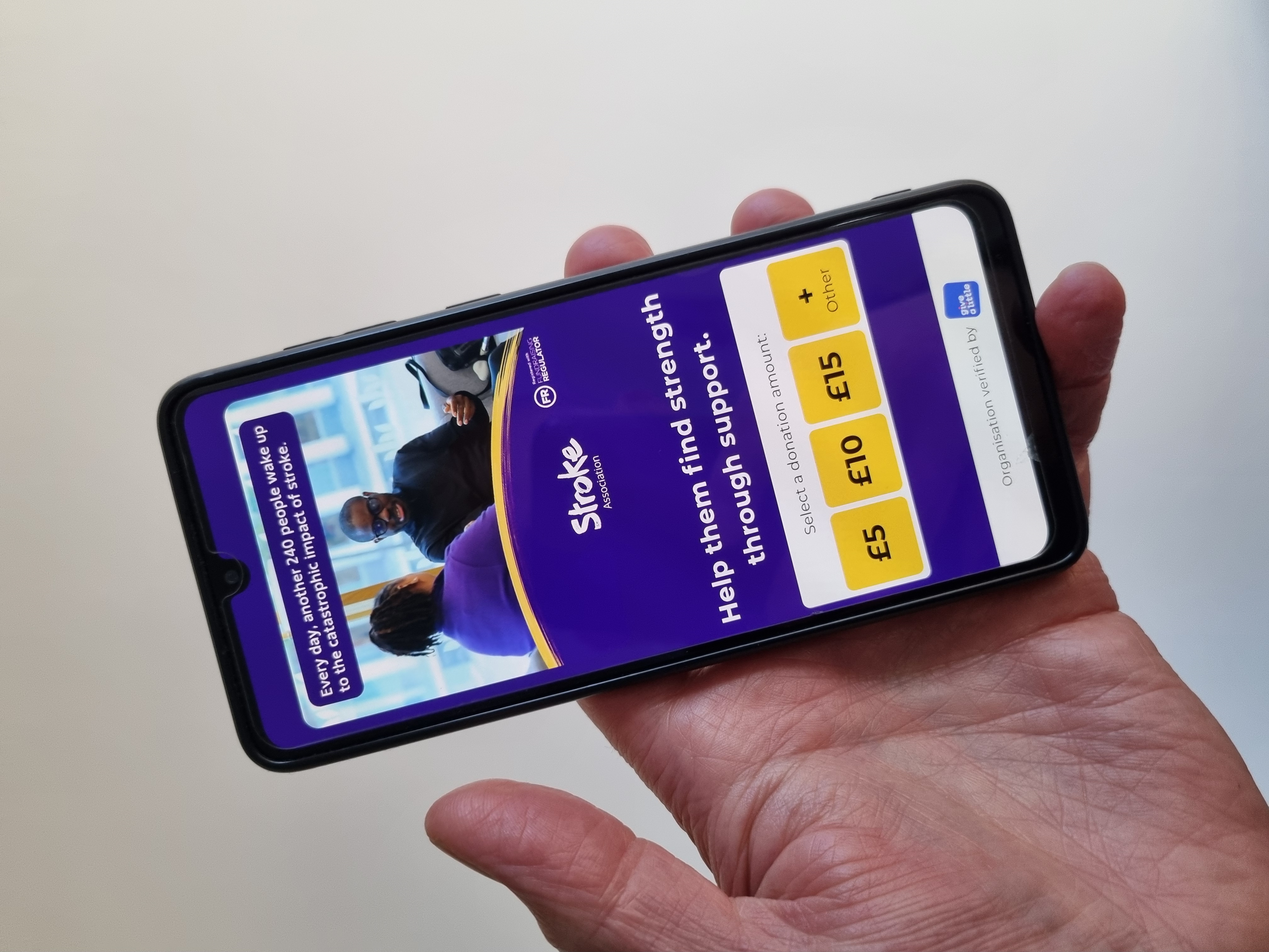 image of a hand holding a mobile phone, with the Give A Little donation app displayed