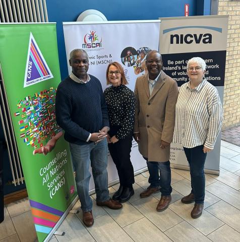 Photo of Lekan Ojo-Okiji Abasi, Counselling All Nations Services (CANS), Sandra Bailie NICVA; Jashwill Emmanuel, Multi-Ethnic Sports & Cultures NI (MSCNI); and Lynda Gould, NICVA; standing together in NICVA's foyer, smiling to the camera.