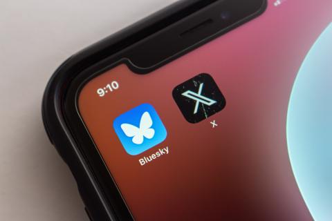 A photo of a phone showing Bluesky and X app icons