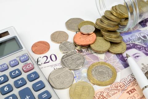 Photo of money beside a calculator and pen.