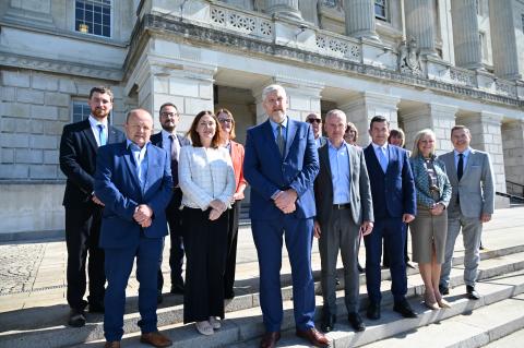 Minister John O'Dowd with NICVA and business bodies on steps of Stormont